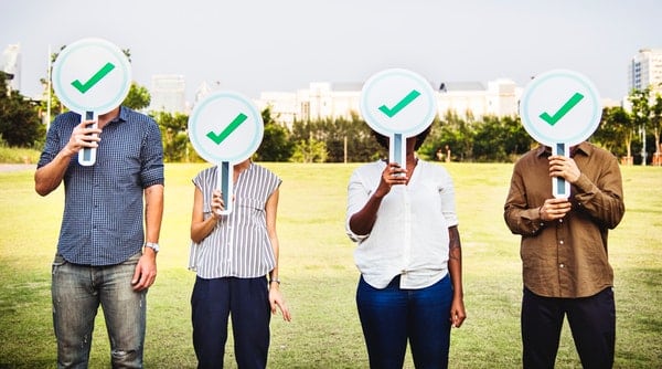 four person holding green check signs standing