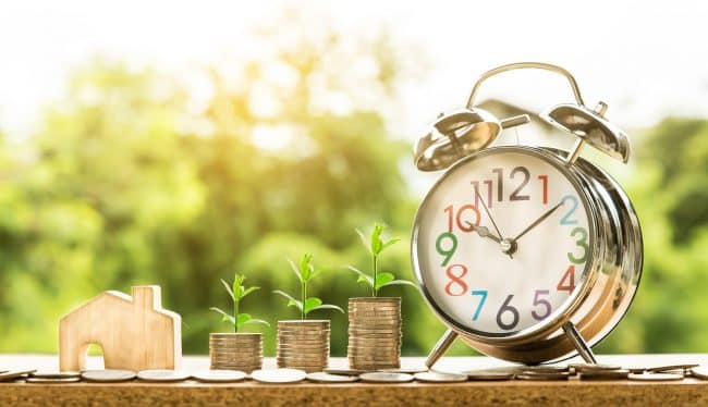 scattered coins in a table and alarm clock