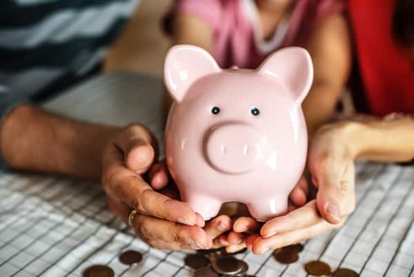 couple holding a piggybank with coins in table